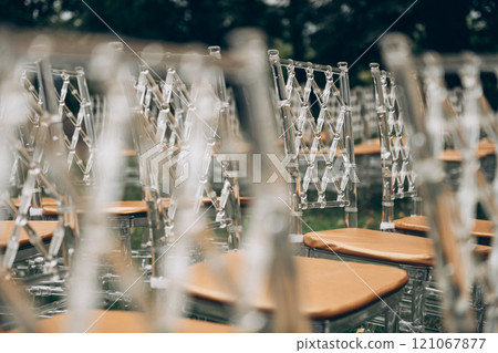 A neat row of clear chairs with wooden seats is wellorganized 121067877