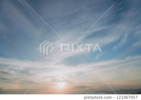 As the sun sets, it shines beautifully through the clouds in the sky 121067957