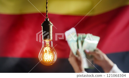 Glowing Edison Light Bulb On Germany Flag. Woman Counting Euros, Deutschland. Glowing Edison Light Bulb On Germany Flag. Woman Counting Euros, Deutschland. 121068304