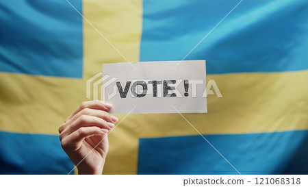 Woman Holding Title Sign With Text Vote On Swedish Flag Background. General Woman Holding Title Sign With Text Vote On Swedish Flag Background. General 121068318
