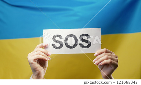 Female Hands With Sos, Alarm, Emergency Card On Ukrainian National Flag 121068342