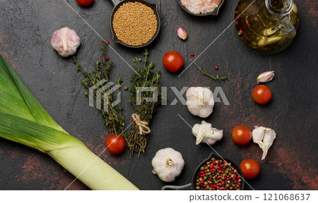 Black table with spices, red cherry tomatoes and mustard seeds 121068637