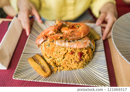 Arroz marinero Ecuadorian cuisine, traditional food, rice recipe with seafood. Hands closeup eating 121069317