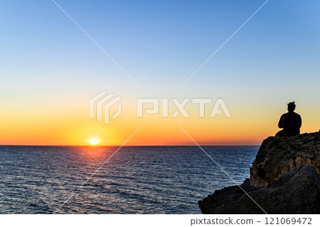 Young man watching the sunset on the Barbate beach next to the Trafalgar lighthouse, Cadiz	 121069472