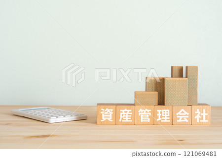 Blocks with the words "asset management company" written on them, a calculator, and a model of a real estate property 121069481