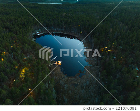Experience a stunning aerial view of a serene forest lake at dusk with a beautiful sky 121070091
