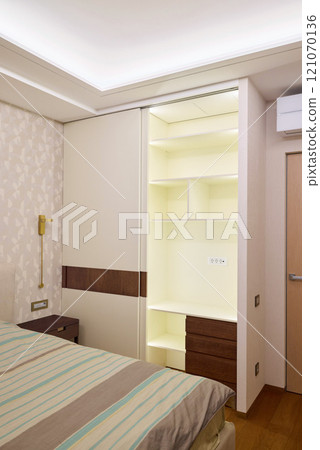 Modern bedroom interior with a builtin wardrobe and soft, inviting lighting for warmth 121070136