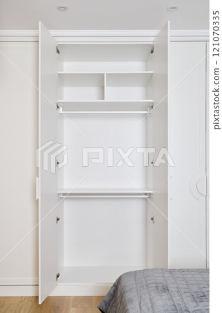 A Stylish and Modern Minimalist Wardrobe Featuring Organized Shelves and a Hanging Rod 121070335