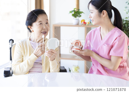 Senior woman receiving tooth brushing instruction from dental hygienist Senior woman receiving tooth brushing instruction from dental hygienist 121071878