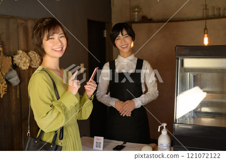 A woman paying with her smartphone at a store A woman paying with her smartphone at a store 121072122