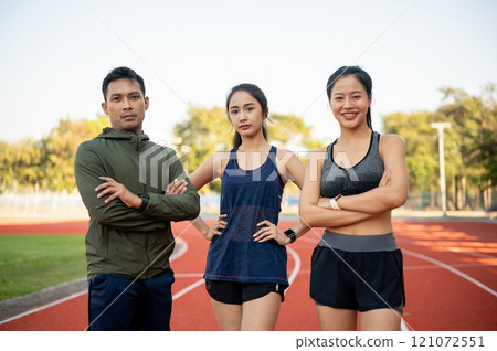 Confident Asian athlete runners in sportswear, standing with their arms crossed in a stadium. Confident Asian athlete runners in sportswear, standing with their arms crossed in a stadium. 121072551
