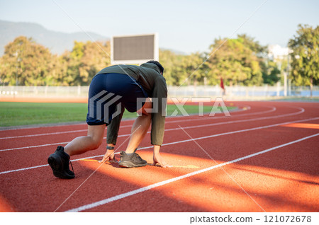 A cropped image of a strong man athletic runner in sportswear training in a stadium in the morning. 121072678