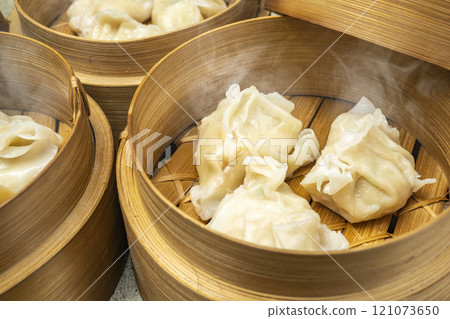Assorted chinese dim sum dumpling on bamboo wooden basket bowl on wooden table 121073650