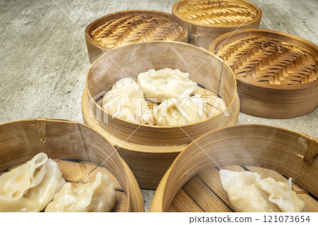 Assorted chinese dim sum dumpling on bamboo wooden basket bowl on wooden table 121073654