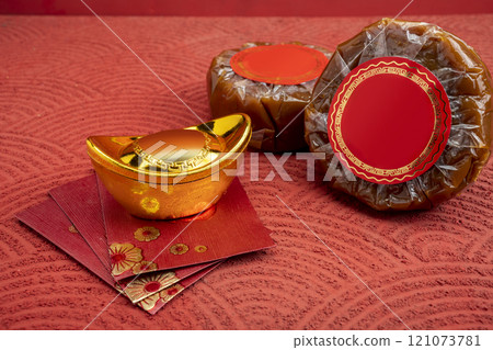 Chinese New Year rice cake or Nian Gao with angpao and Chinese gold ingot on a red background 121073781