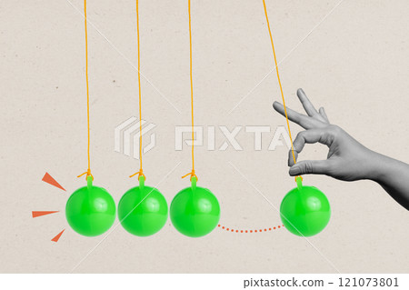 A human hand pulling a balancing ball on a pendulum on a colored background 121073801