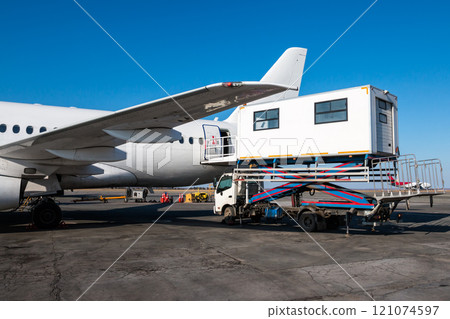 Ambulift truck for people with disabilities is at the passenger airplane Ambulift truck for people with disabilities is at the passenger airplane 121074597