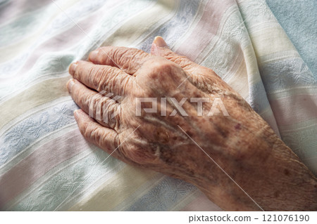 Winkled hand of an 100 old senior elderly women resting peacefully on hospital bedding. Concept of life, aging, health, illness, dignity, compassion, dying ... 121076190