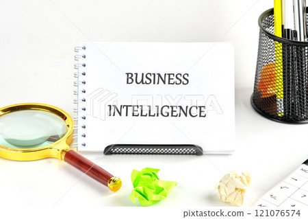 Business intelligence tools displayed on a desk with stationery and a magnifying glass 121076574