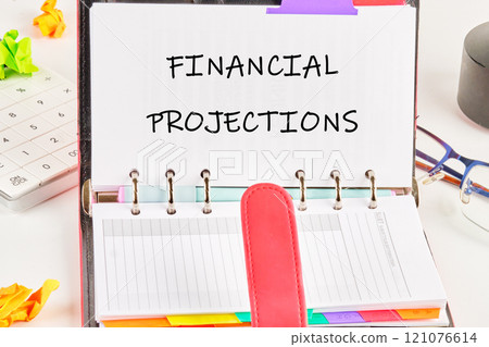 Financial projections notebook open on a desk with stationery and a calculator nearby Financial projections notebook open on a desk with stationery and a calculator nearby 121076614