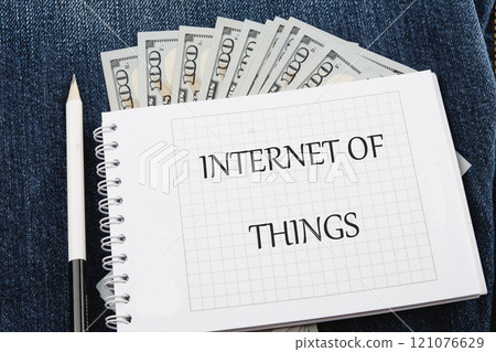 The concept of technology and development. Phrase, words, text INTERNET OF THINGS on a blank sheet of notepad against the background of dollar bills The concept of technology and development. Phrase, words, text INTERNET OF THINGS on a blank sheet of notepad against the background of dollar bills 121076629