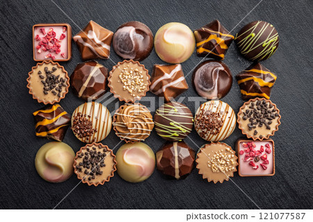 Mix of chocolate pralines on black table. Top view. Mix of chocolate pralines on black table. Top view. 121077587