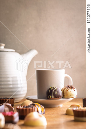Mix of chocolate pralines and coffee cup on wooden table. 121077596
