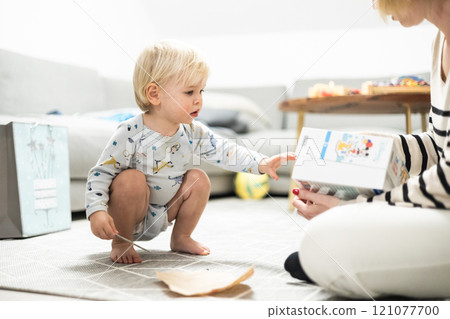 Parents playing games with child. Little toddler doing puzzle. Infant baby boy learns to solve problems and develops cognitive skills. Child development concept. 121077700