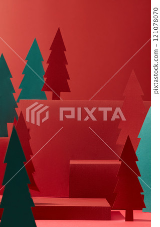 A frontal view of red cube podiums with empty space for product showcase, decorated by paper Noel trees with different sizes and colors, suitable for the Christmas concept in a crimson backdrop. 121078070