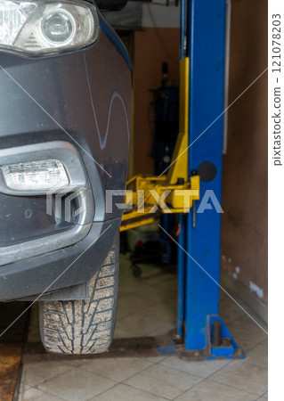 Gray car on auto lift in garage for repair and maintenance service. Gray car on auto lift in garage for repair and maintenance service. 121078203