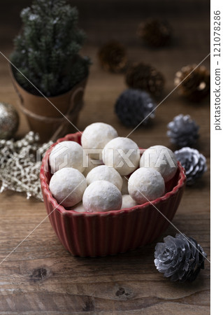 Snowball cookies served in a red dish and a table decorated for Christmas 121078286
