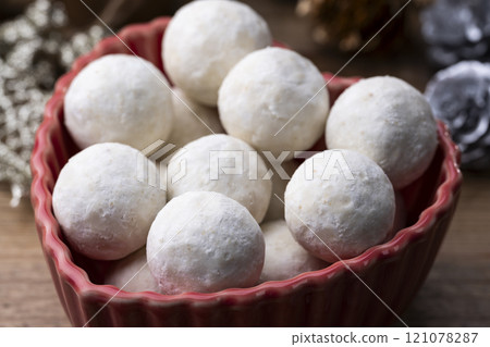 Snowball cookies served in a red dish and a table decorated for Christmas 121078287