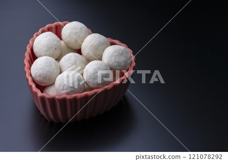 Heart-shaped red bowl and snowball cookies on a black background Heart-shaped red bowl and snowball cookies on a black background 121078292