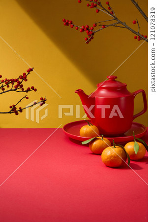 On a yellow backdrop, a close-up of a crimson display product table decorated by winterberry branches, a red teapot, and a red dish of tangerines. A template image with an idea of the Chinese New Year On a yellow backdrop, a close-up of a crimson display product table decorated by winterberry branches, a red teapot, and a red dish of tangerines. A template image with an idea of the Chinese New Year 121078319