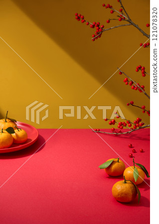 A close-up of a crimson table for display products, decorated with a red plate of tangerines and an Ilex verticillata branch, on a yellow backdrop. A template photo about the Chinese New Year concept. A close-up of a crimson table for display products, decorated with a red plate of tangerines and an Ilex verticillata branch, on a yellow backdrop. A template photo about the Chinese New Year concept. 121078320