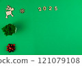 Spread on a green background chroma key, on the left there is a wooden deer with branchy antlers, a green office flower made of moss in a white pot and a red shiny gift bow, on top there is a wooden 121079108