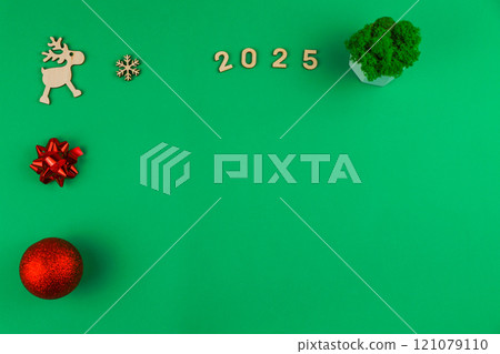 Spread on a green background chroma key on the left there is a wooden deer with branchy antlers, a red bow and a red shiny New Year's ball, on top there is a wooden snowflake, 2025 inscription in Spread on a green background chroma key on the left there is a wooden deer with branchy antlers, a red bow and a red shiny New Year's ball, on top there is a wooden snowflake, 2025 inscription in 121079110