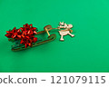 A wooden deer with antlers is carrying a green wooden sleigh on which there are red holiday bows, gifts on a bright green background. High quality photo 121079115