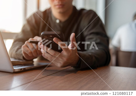 A close-up of a businessman using his smartphone at a table in the office. 121080117