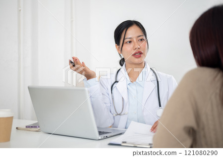 A doctor talking with a patient in the examination room, listening to the patient's symptoms. 121080290