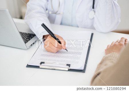 A close-up of a doctor filling out a medical form while examining a patient. A close-up of a doctor filling out a medical form while examining a patient. 121080294