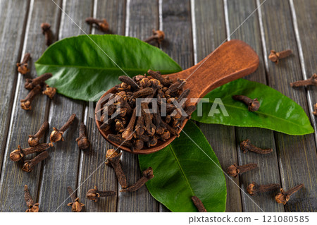 Dry clove buds in a brown wooden spoon macro. 121080585