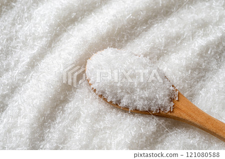 Monosodium glutamate in a wooden spoon over E621 white crystals background. Monosodium glutamate in a wooden spoon over E621 white crystals background. 121080588