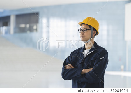 A man in his 40s wearing work clothes and a helmet 121081624