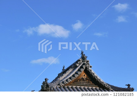 Temple ridgepole tiles and shachihoko statues standing out against the blue sky Temple ridgepole tiles and shachihoko statues standing out against the blue sky 121082185