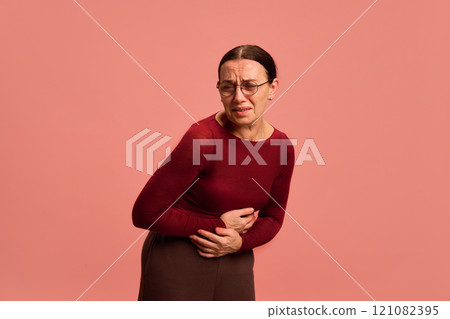 Female health. Woman sick unhappy holding uterus pain, reproductive system against pastel peach background. Female health. Woman sick unhappy holding uterus pain, reproductive system against pastel peach background. 121082395