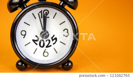 Business concept of 2025 new year symbol. Beautiful orange paper with number 2025. Beautiful orange background, copy space. Black alarm clock. Business 2025 happy new year concept. 121082765