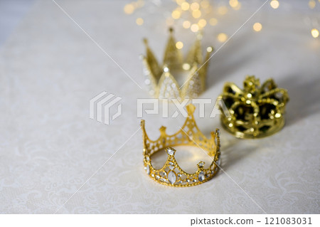 Epiphany Day or Dia de Reyes Magos concept. Three gold crowns on light sparkling background Epiphany Day or Dia de Reyes Magos concept. Three gold crowns on light sparkling background 121083031