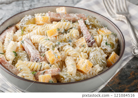 Italian Fusilli pasta salad with pickles, yellow cheese, dill and bacon dressed with mayonnaise close-up in a bowl. Horizontal 121084516