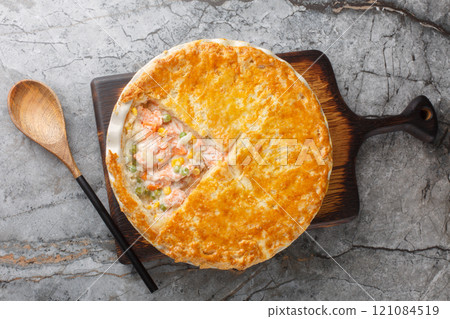 Festive fish Pot Pie with salmon, carrots, corn, onion and peas and in a buttery pie crust closeup on the baking dish. Horizontal top view 121084519